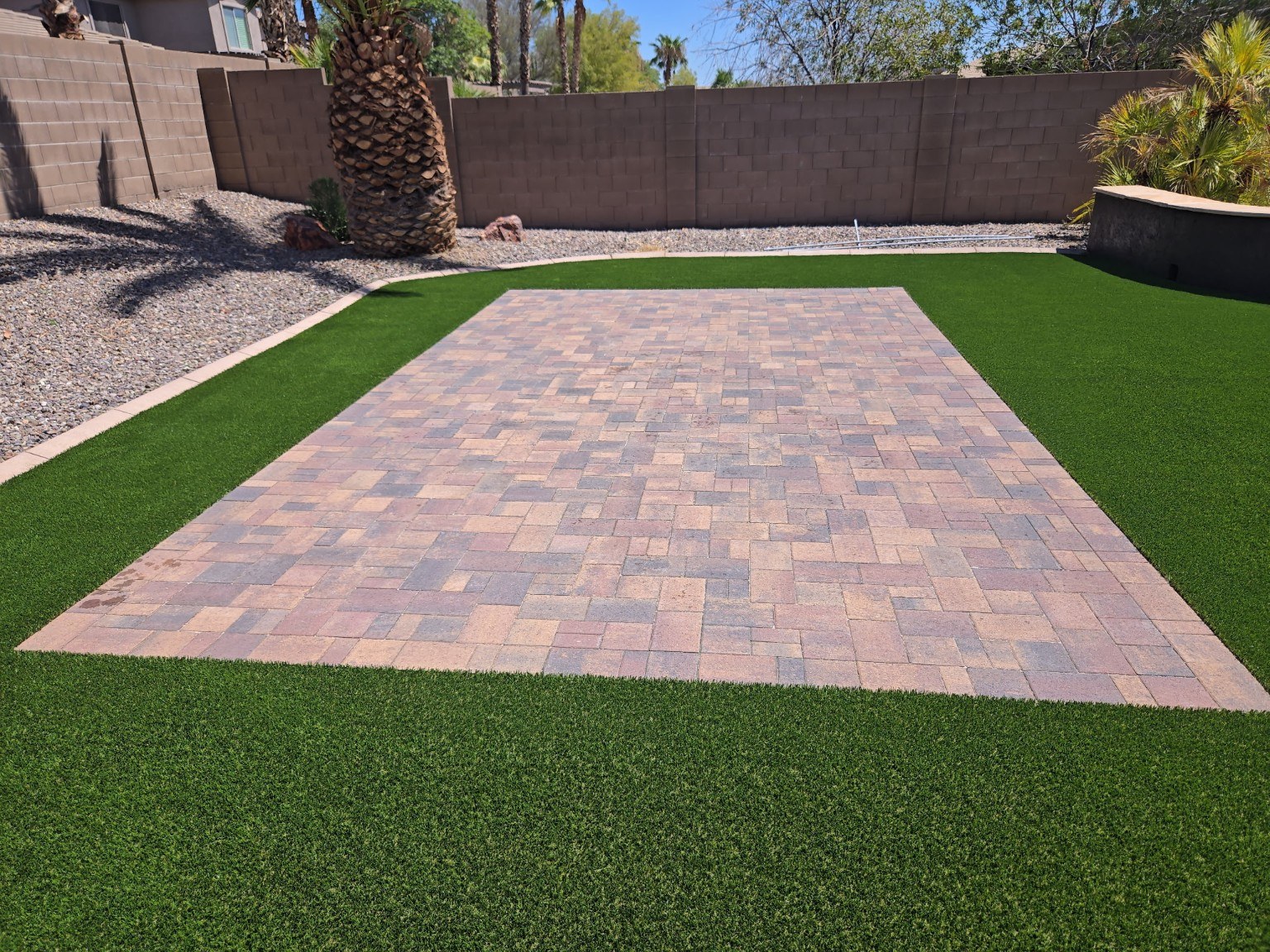 Completed paver patio surrounded by artificial turf