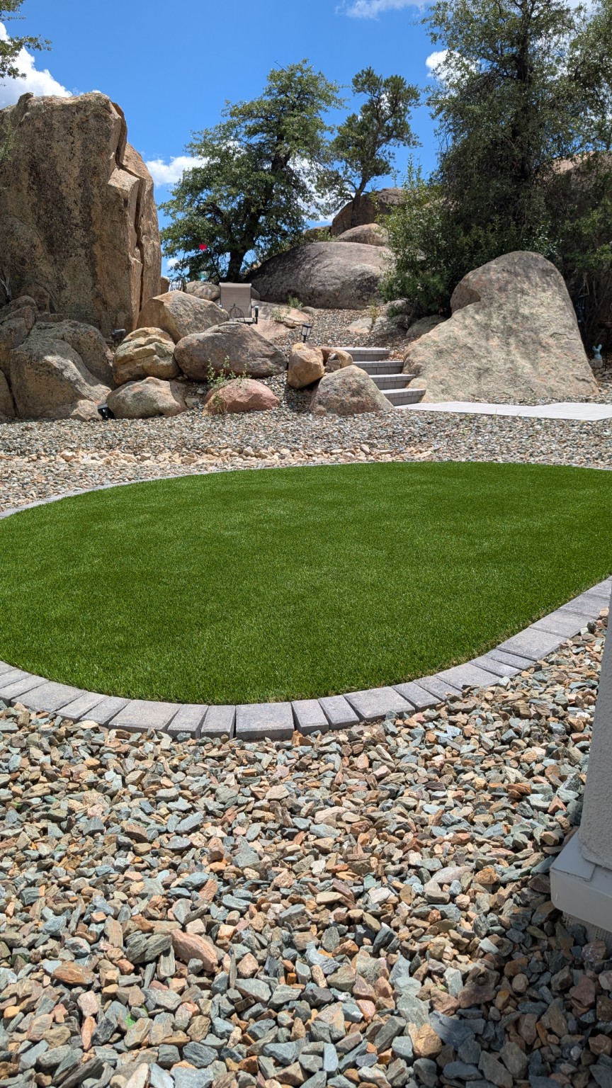 Artificial turf lawn with curved paver border and natural boulders